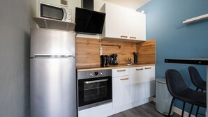 A compact kitchen with a built-in microwave, oven, and coffee maker. - Le studio epure du commandant (Évreux)