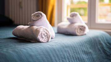 A bed with rolled towels and a window with curtains.