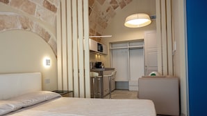 A modern hotel room with a bed, a small kitchenette, and a bathroom. - Iris Apartments (Monopoli)