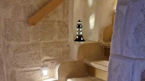 A staircase with a wooden handrail, a small lighthouse decoration, and a doormat with the word "BIRDS" on it. - Iris Apartments (Monopoli)