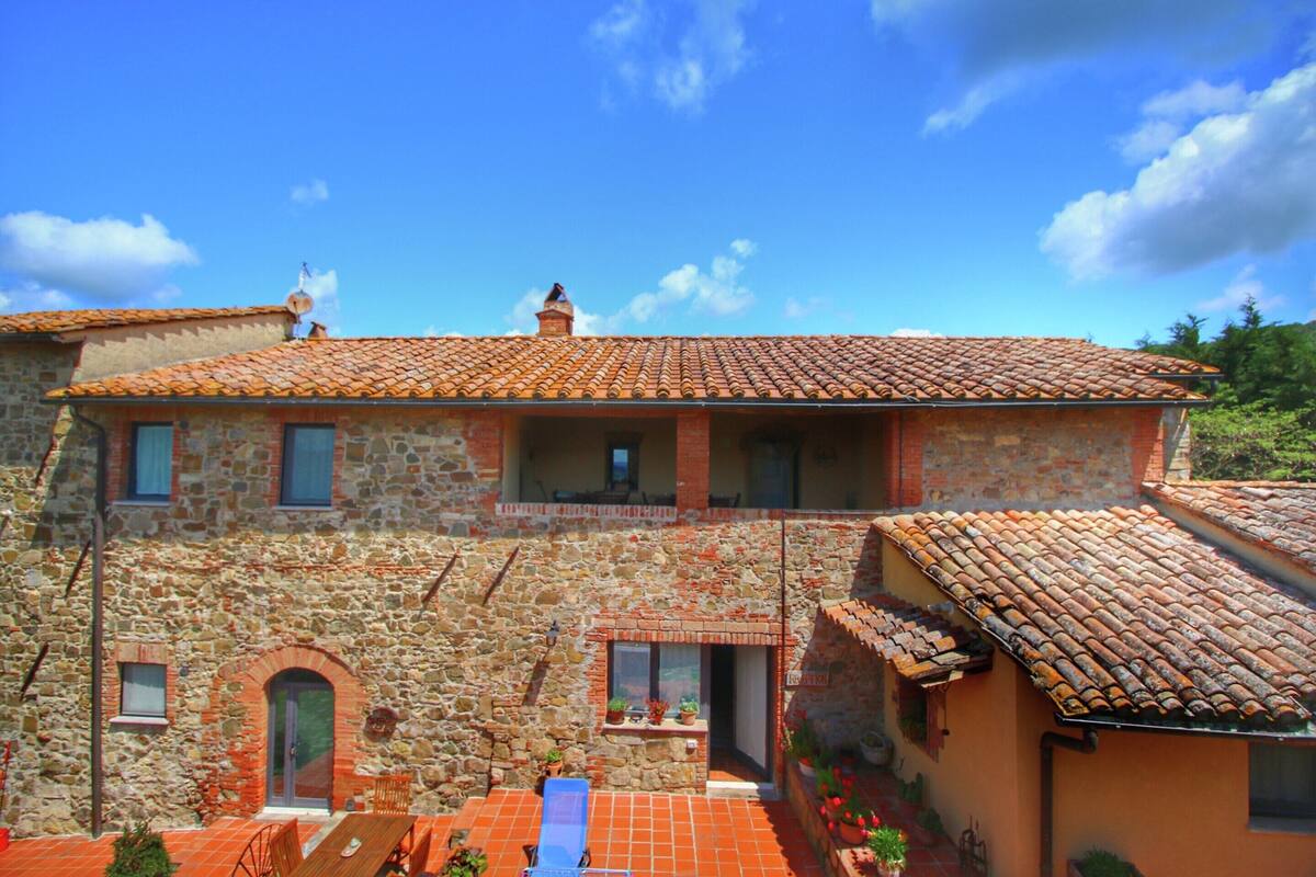 A stone building with a tiled roof, a balcony, and a small window.