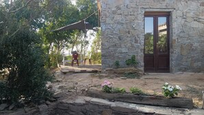 Edificio de piedra con puerta de madera y un pequeño jardín lleno de flores.