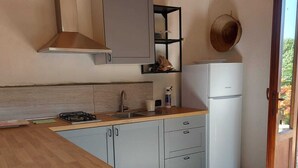 Una cocina con una mesa de madera, armarios blancos y una estufa empotrada.