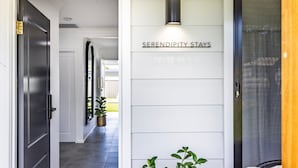 Een gang met een bord waarop “SERENDIPITY STAYS” staat en een deur met een muggenet.