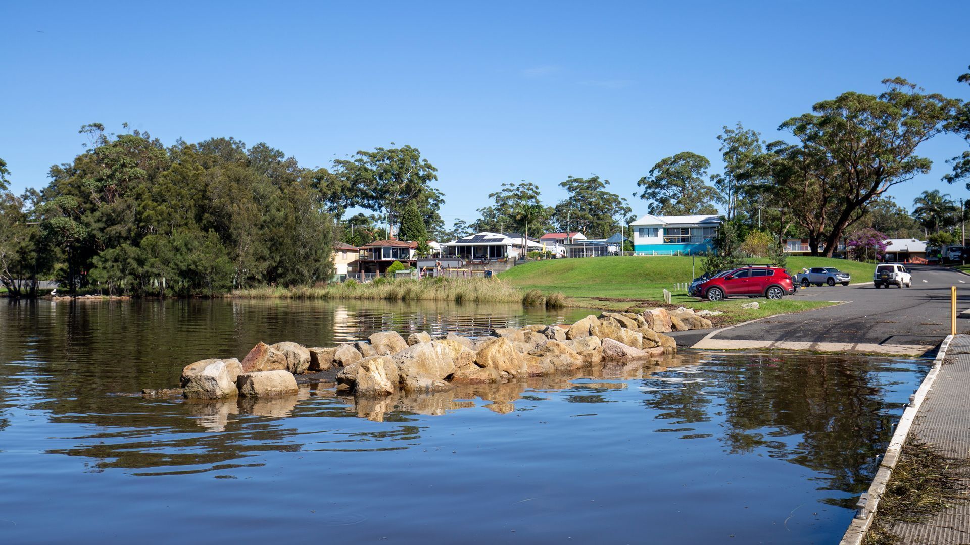A lakeside property with a dock, a paved walkway, and a row of houses with a blue building.