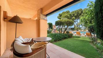Un patio con mesa y sillas, una lámpara y vistas a una piscina y jardín.