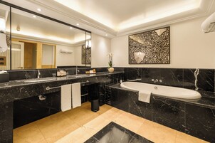 Een moderne badkamer met een zwart marmeren wastafelmeubel, een grote spiegel, een vrijstaand bad en een geometrisch wanddecoratie.
