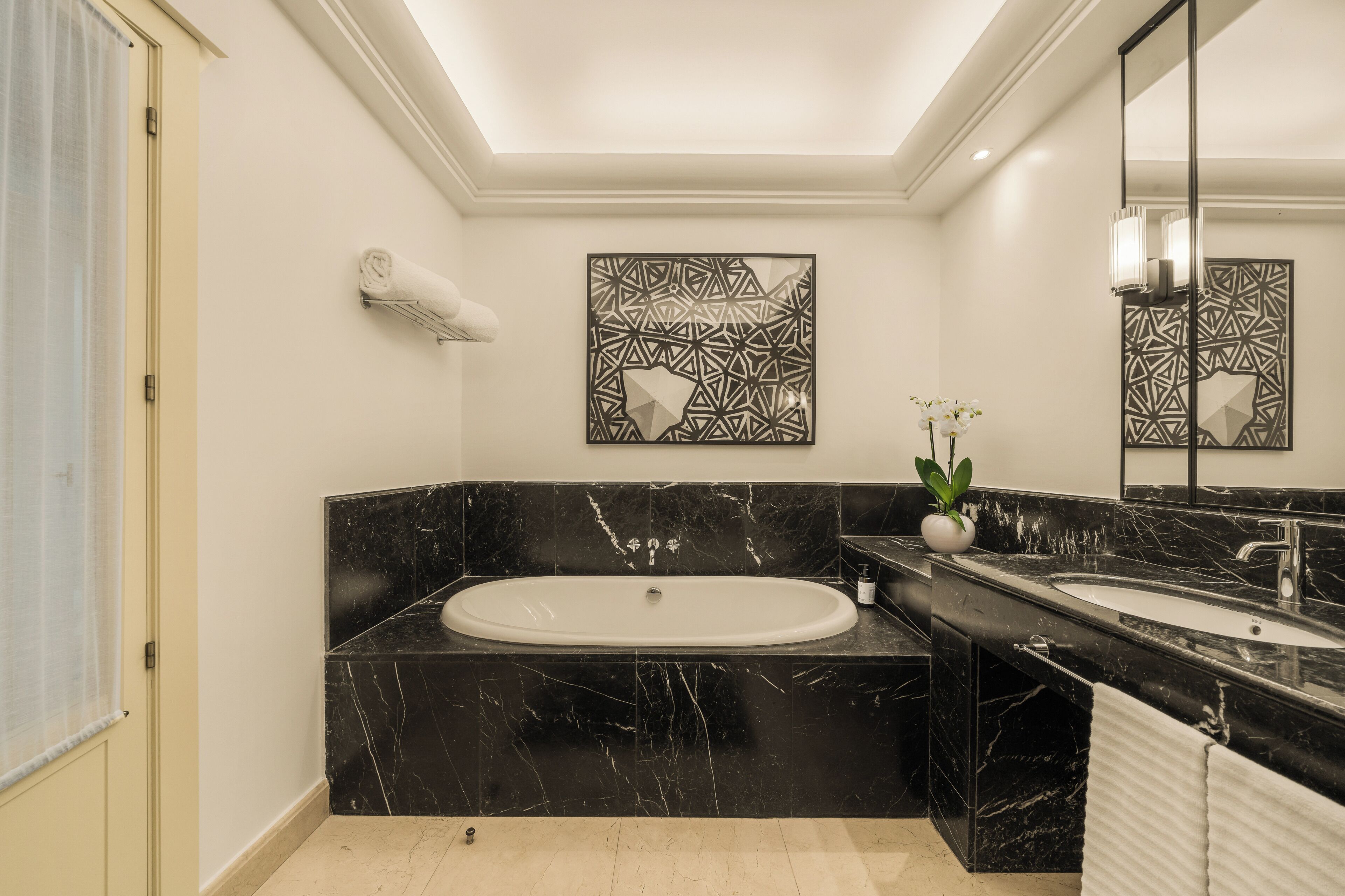 Ein modernes Badezimmer mit einer großen Badewanne, einem Doppelwaschbecken und einem dekorativen Wandbild.