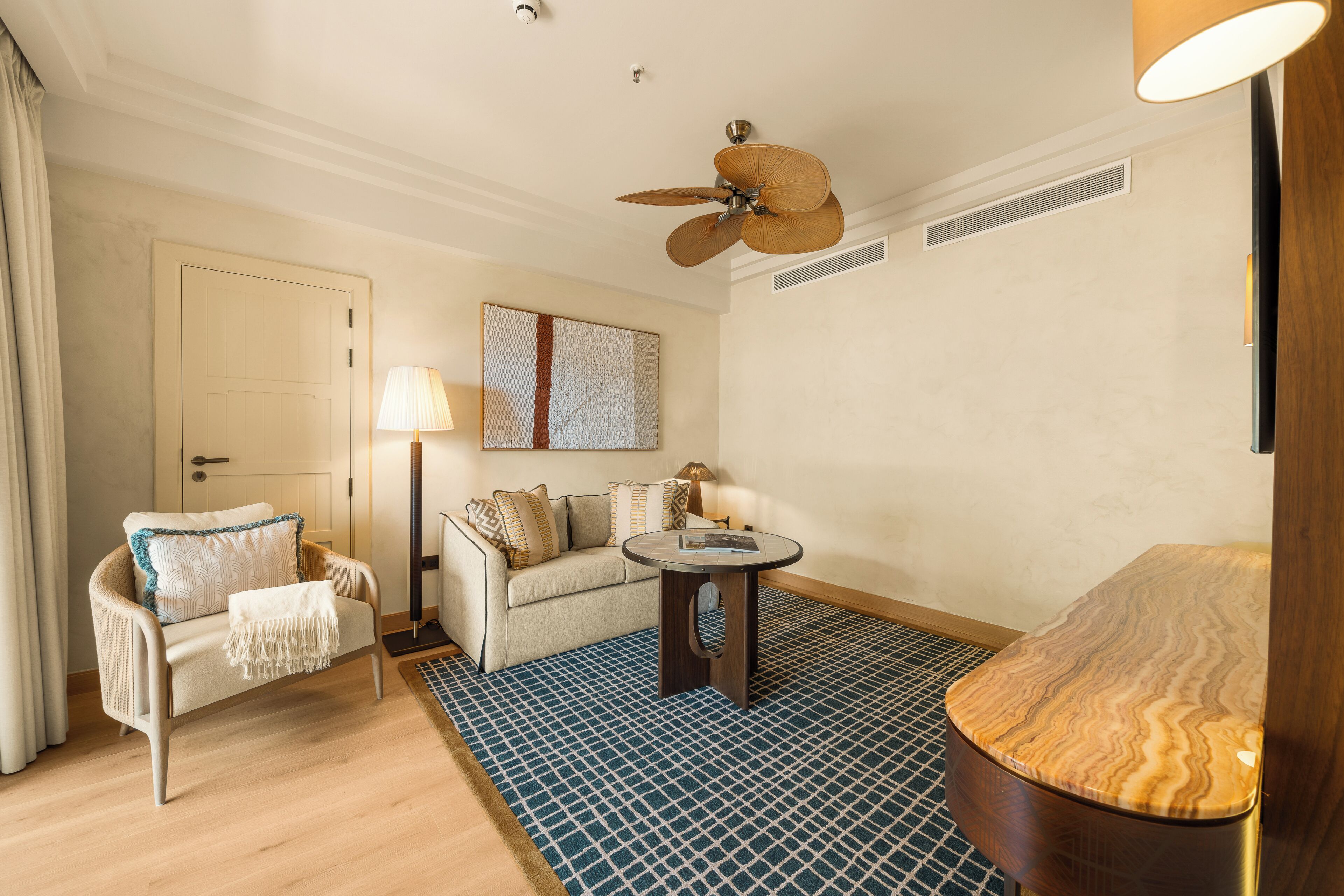 Un salon moderne avec un canapé, une table basse, un lampadaire et un ventilateur de plafond.