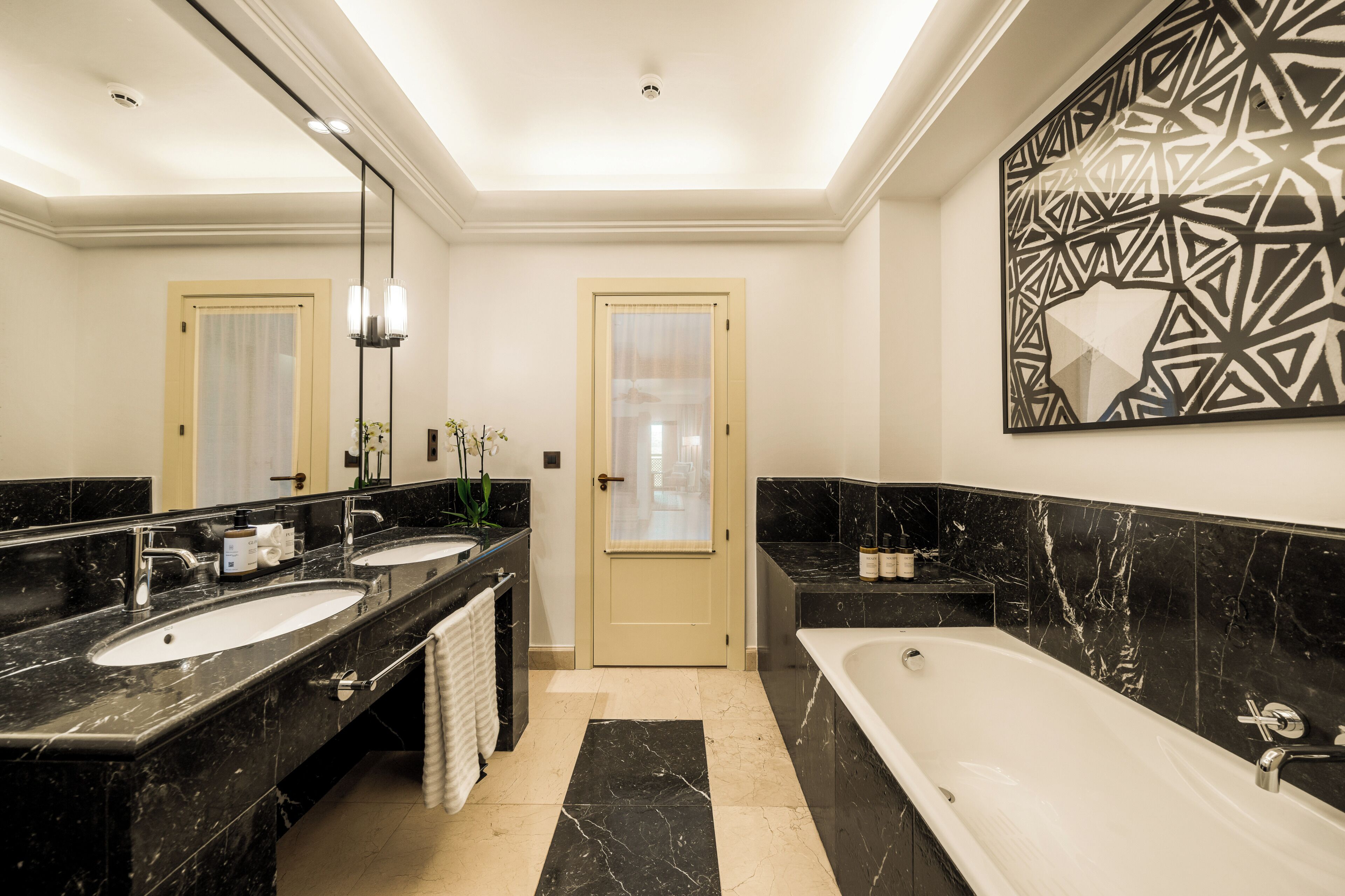Un baño moderno con dos lavamanos, una bañera y un espejo grande.