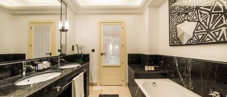 A modern bathroom with two sinks, a bathtub, and a large mirror.