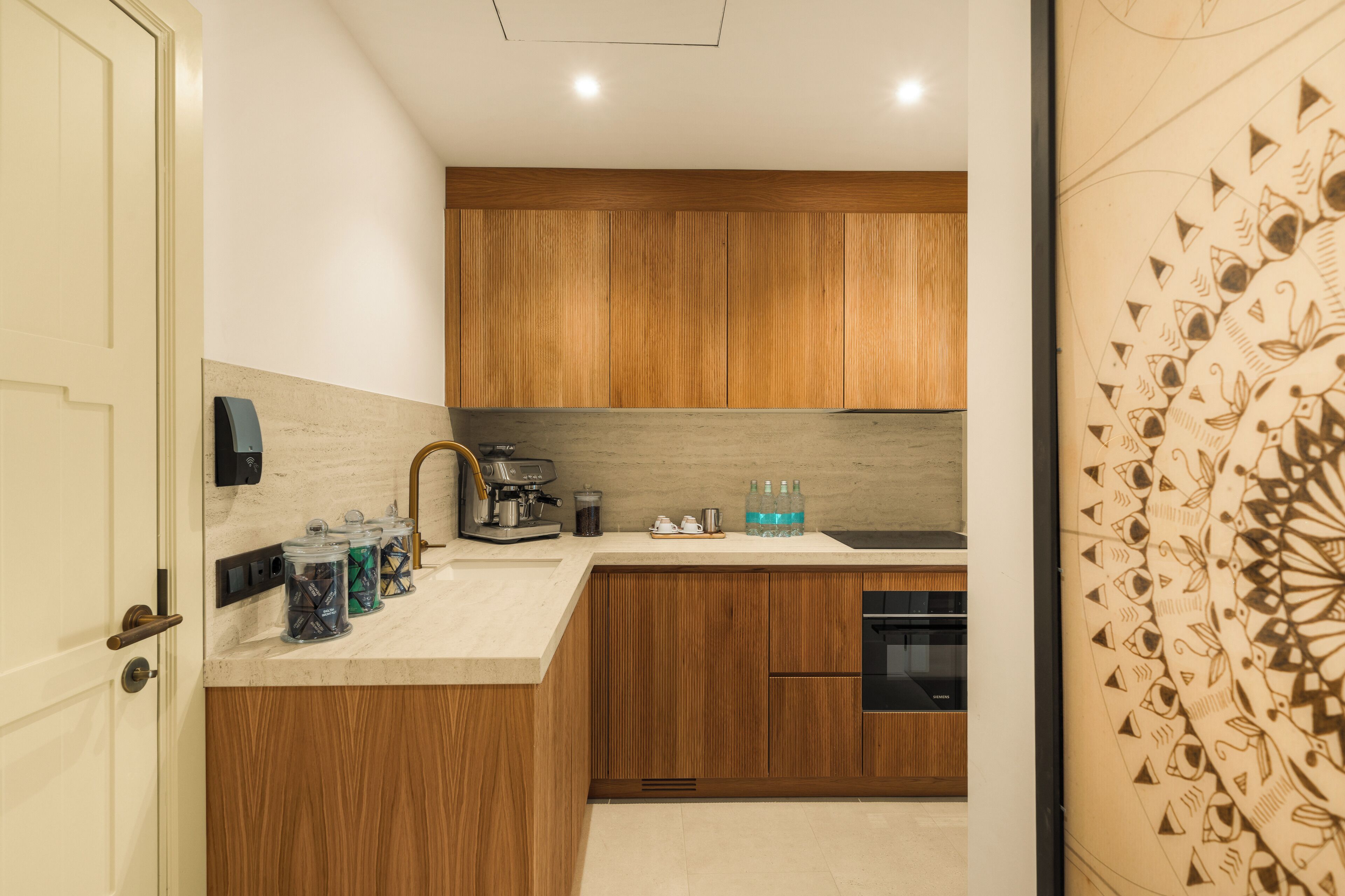 A modern kitchen with wooden cabinets, a built-in espresso machine, and a stainless steel sink.