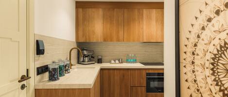 A modern kitchen with wooden cabinets, a built-in espresso machine, and a stainless steel sink.