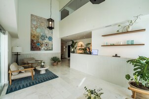 Een hotel lobby met een receptiebalie, een zithoek en decoratieve muurkunst.
