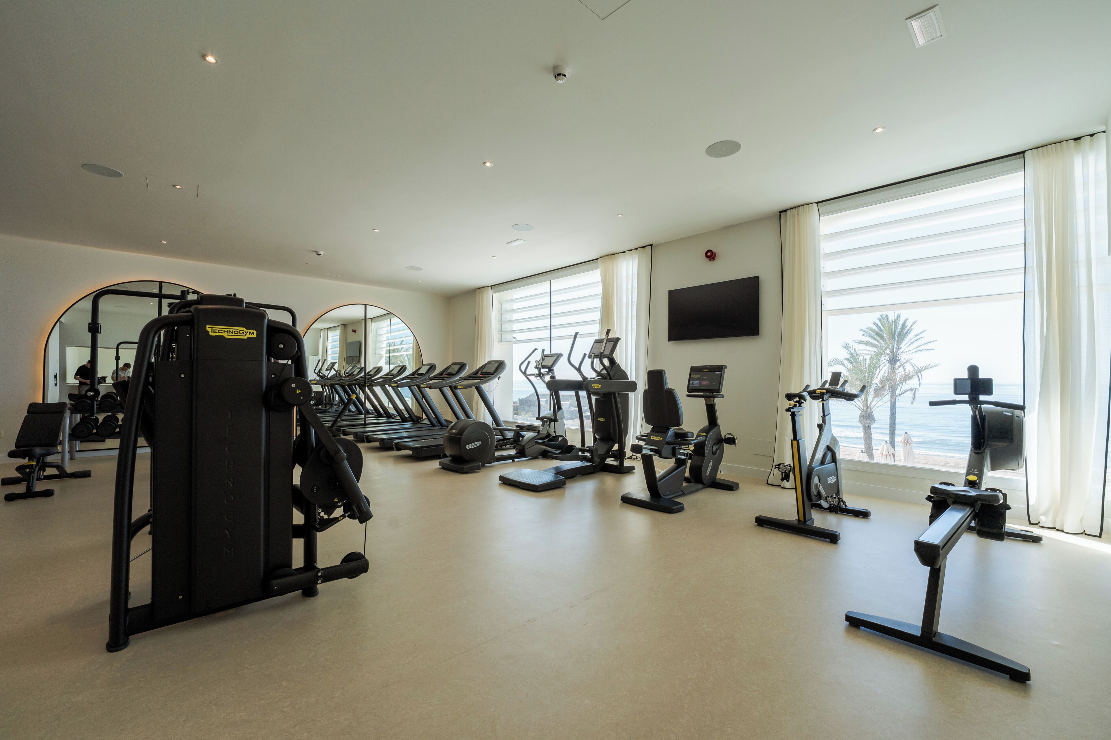 A gym with treadmills, elliptical machines, and weight equipment.