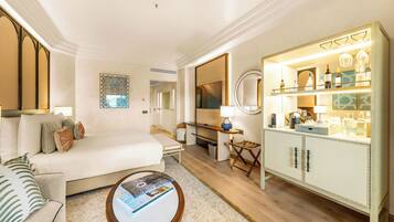 A hotel room with a bed, a desk, a minibar, and a seating area with a coffee table.
