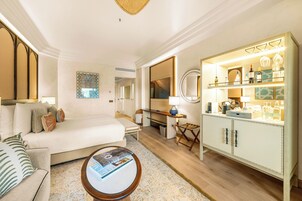 Een hotelkamer met een bed, een bureau, een minibar en een zithoek met een salontafel.