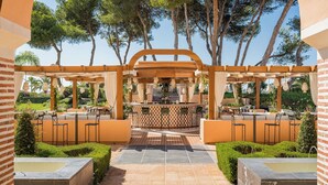 An outdoor bar area with a central counter, surrounded by seating arrangements and a pergola structure. - Gran Marbella Resort & Beach Club (Marbella)
