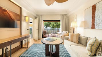 Une chambre d’hôtel dotée d’une grande télévision, d’une table ronde, d’un canapé et offrant une vue sur l’extérieur.