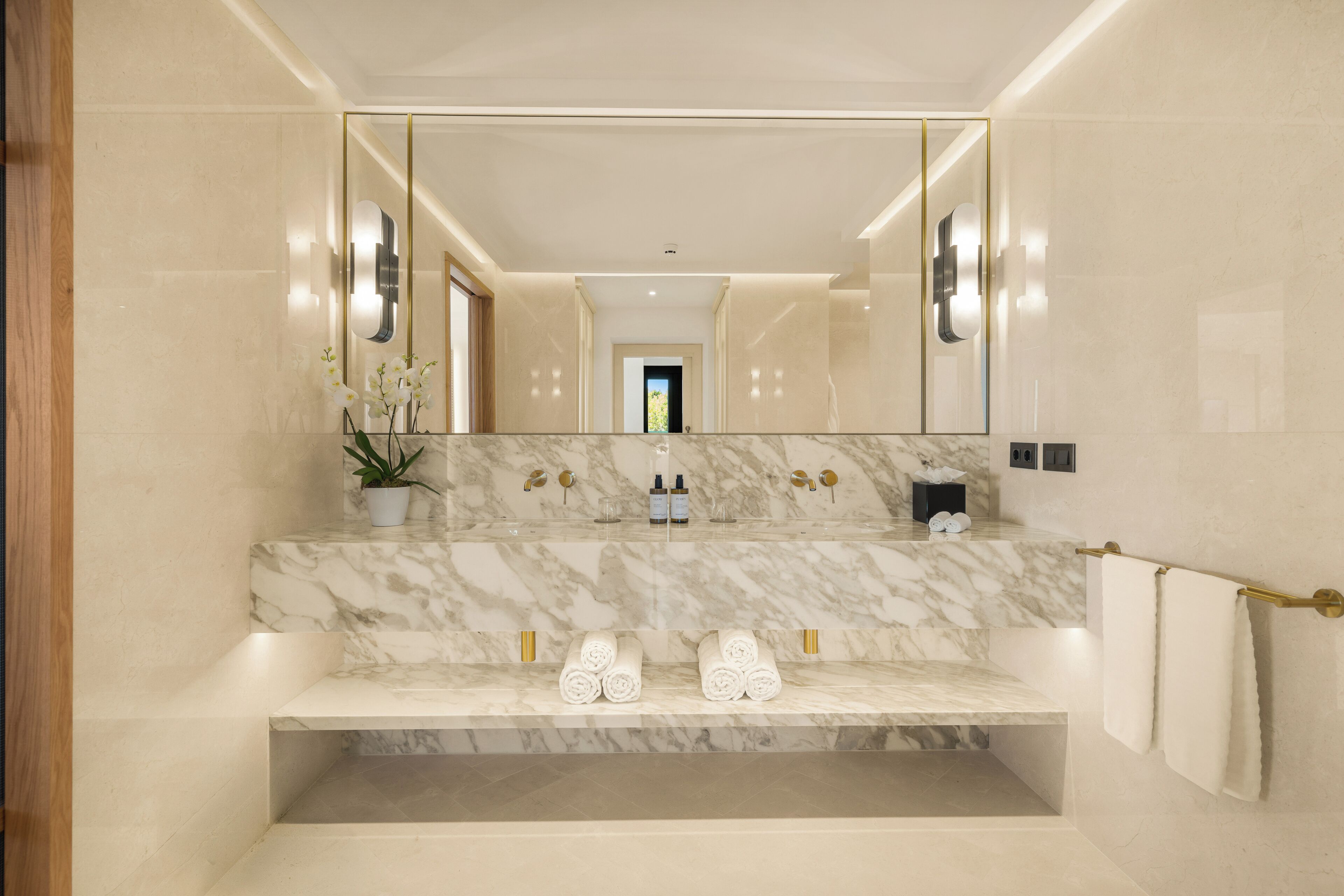 A bathroom with a marble sink, a large mirror, and a towel rack.
