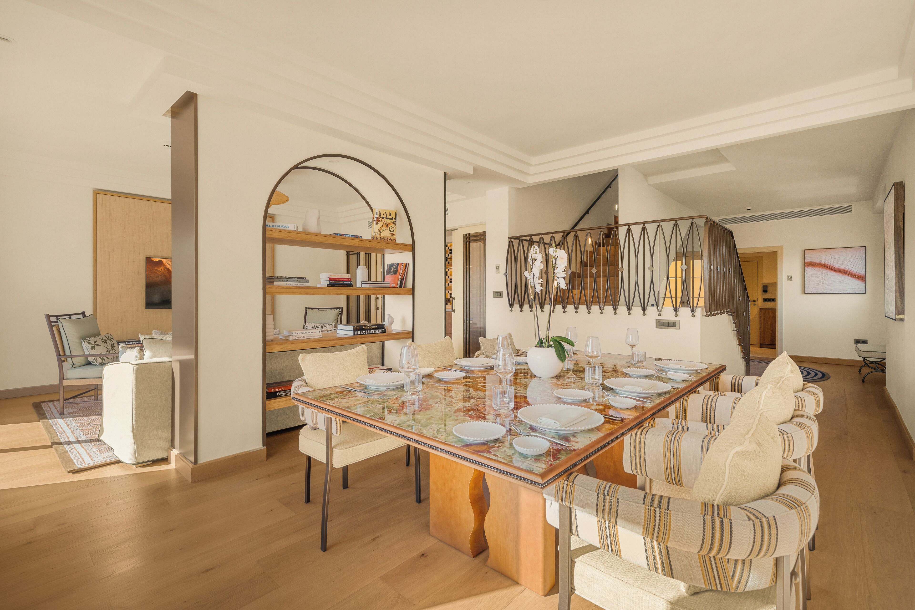 A dining area with a wooden table set for four, surrounded by upholstered chairs.