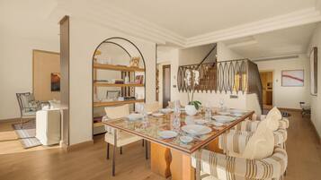 Comedor con una mesa de madera dispuesta para cuatro personas, rodeada de sillas tapizadas.