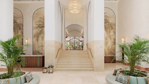 A spacious lobby with a central staircase, two seating areas with plants, and a reception desk. - Gran Marbella Resort & Beach Club (Marbella)