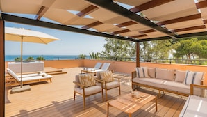A wooden deck with outdoor furniture, a covered seating area, and a view of the sea. - Gran Marbella Resort & Beach Club (Marbella)