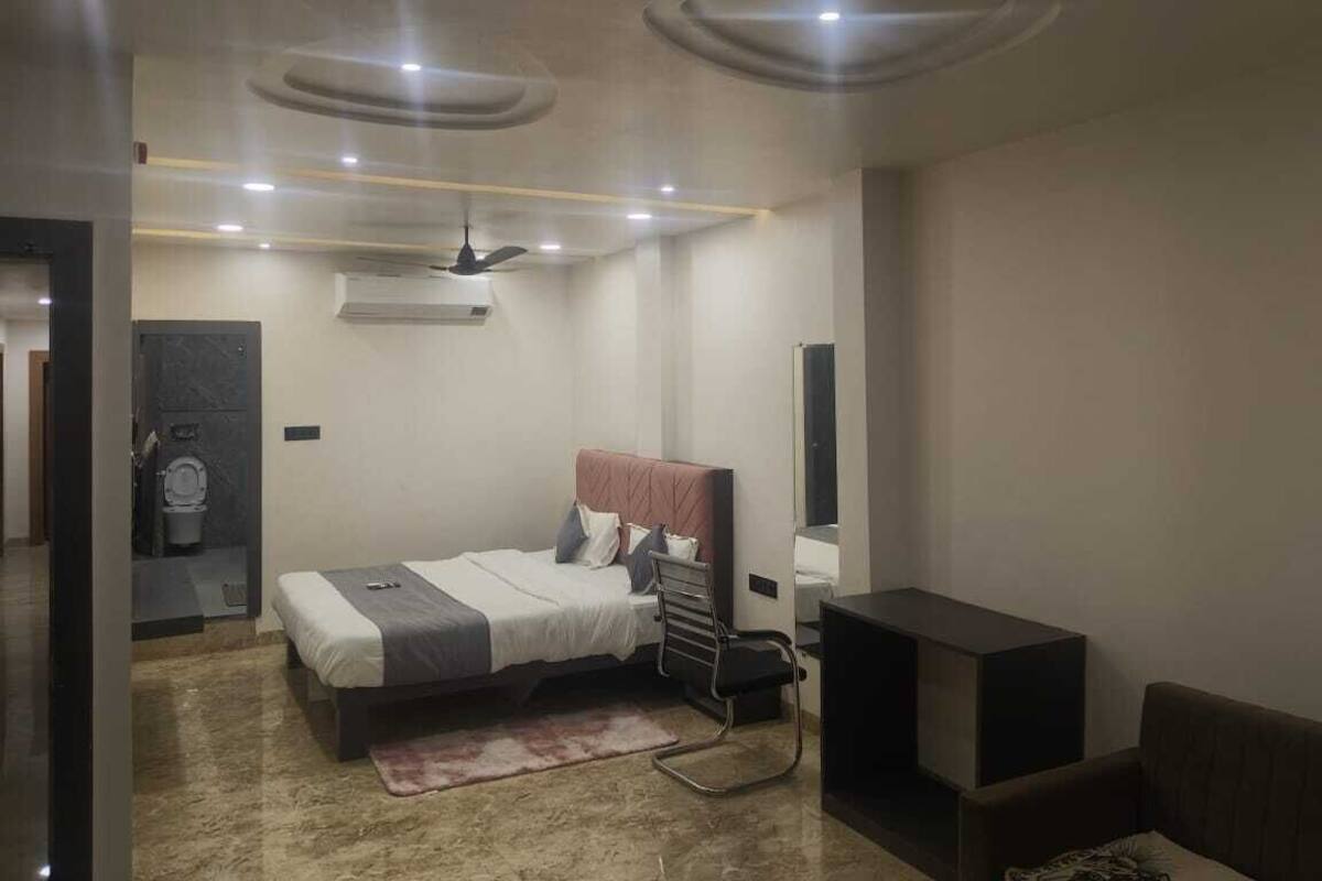 Un dormitorio moderno con cama, escritorio y silla. Hay un ventilador de techo y un equipo de aire acondicionado.