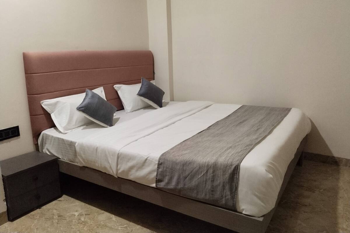 Una cama con cabecera, almohadas y una manta.