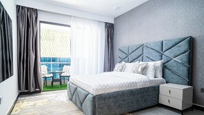 A modern bedroom with a large bed, a nightstand, and a view of a blue outdoor area. - Maskan Airbnbs (Nairobi)