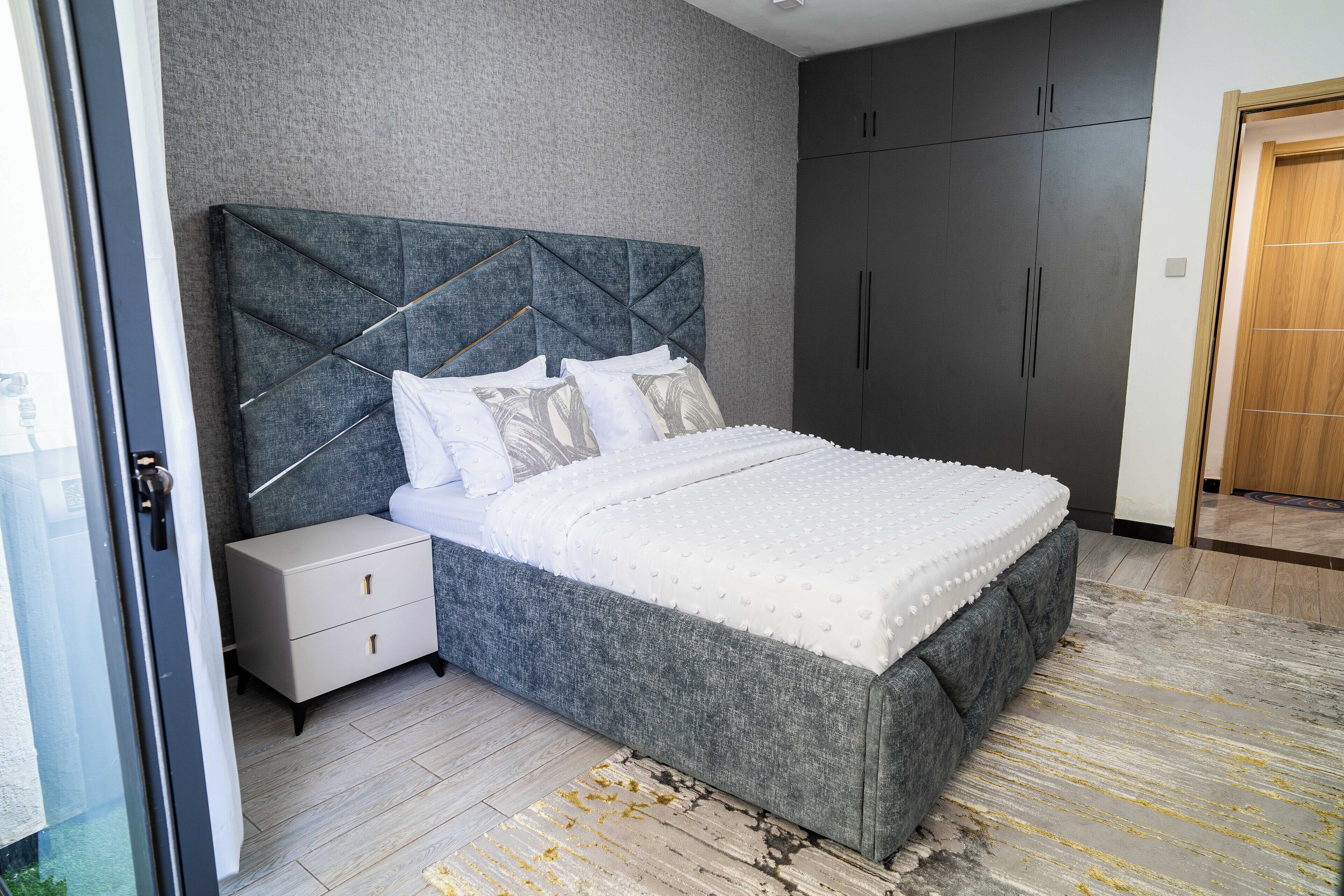 Un dormitorio con cama, mesita de noche, armario y puerta.