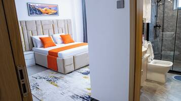 A modern bedroom with a bed, a bathroom with a toilet and shower, and a large window.