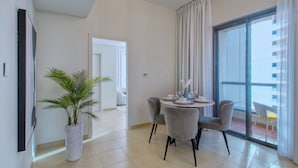 A modern living room with a dining area, a potted plant, and a view of the outside balcony. - Cozy 1BR at Bahar with great view  (Dubai)