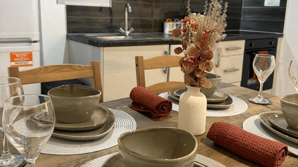 A dining area with a table set for four, including plates, bowls, and glasses. - Deluxe 1 Bed Apartment, London (London)
