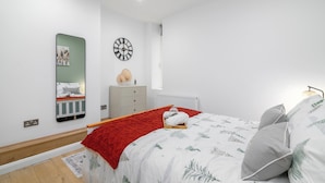 A modern bedroom with a bed, a dresser, a mirror, and a clock on the wall. - Deluxe 1 Bed Apartment, London (London)