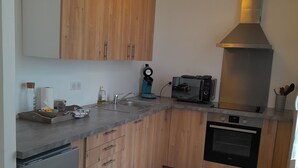 Een moderne keuken met houten kastjes, een inbouwoven, een koffiezetapparaat en een broodrooster.