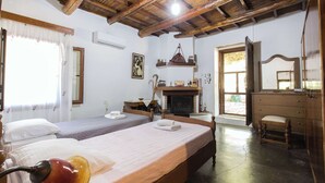 Un dormitorio con dos camas, techo de madera, chimenea, espejo y ventana con cortinas.