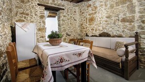 Una habitación con paredes de piedra, una mesa de madera, sillas, un sofá y una planta en maceta.