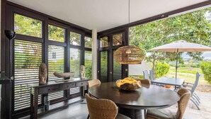 A dining area with a round table, wicker chairs, and a large umbrella.