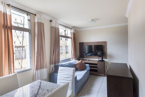 Cozy retreat with a single bed, desk, and TV, perfect for work or relaxation.