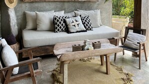 Ein rustikales Interieur mit einer Couch, Sesseln, einem Holztisch und einem Deckenventilator.
