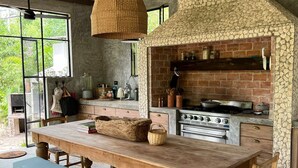 Eine rustikale Küche mit Kamin aus Stein, Holztisch und Bank.