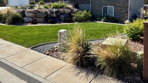 A modern two-story house with a stone facade, a garage, and a well-maintained lawn.