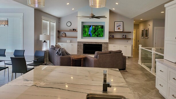 A modern living room with a marble dining table, a sofa, and a TV mounted on the wall.