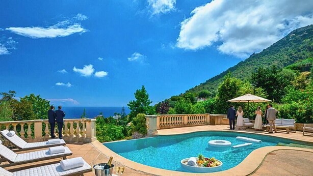 Un espace piscine avec des chaises longues, une table de buffet proposant des fruits et des boissons, et une vue sur la mer.