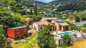 Une villa avec piscine, entourée d’une végétation luxuriante et de collines.