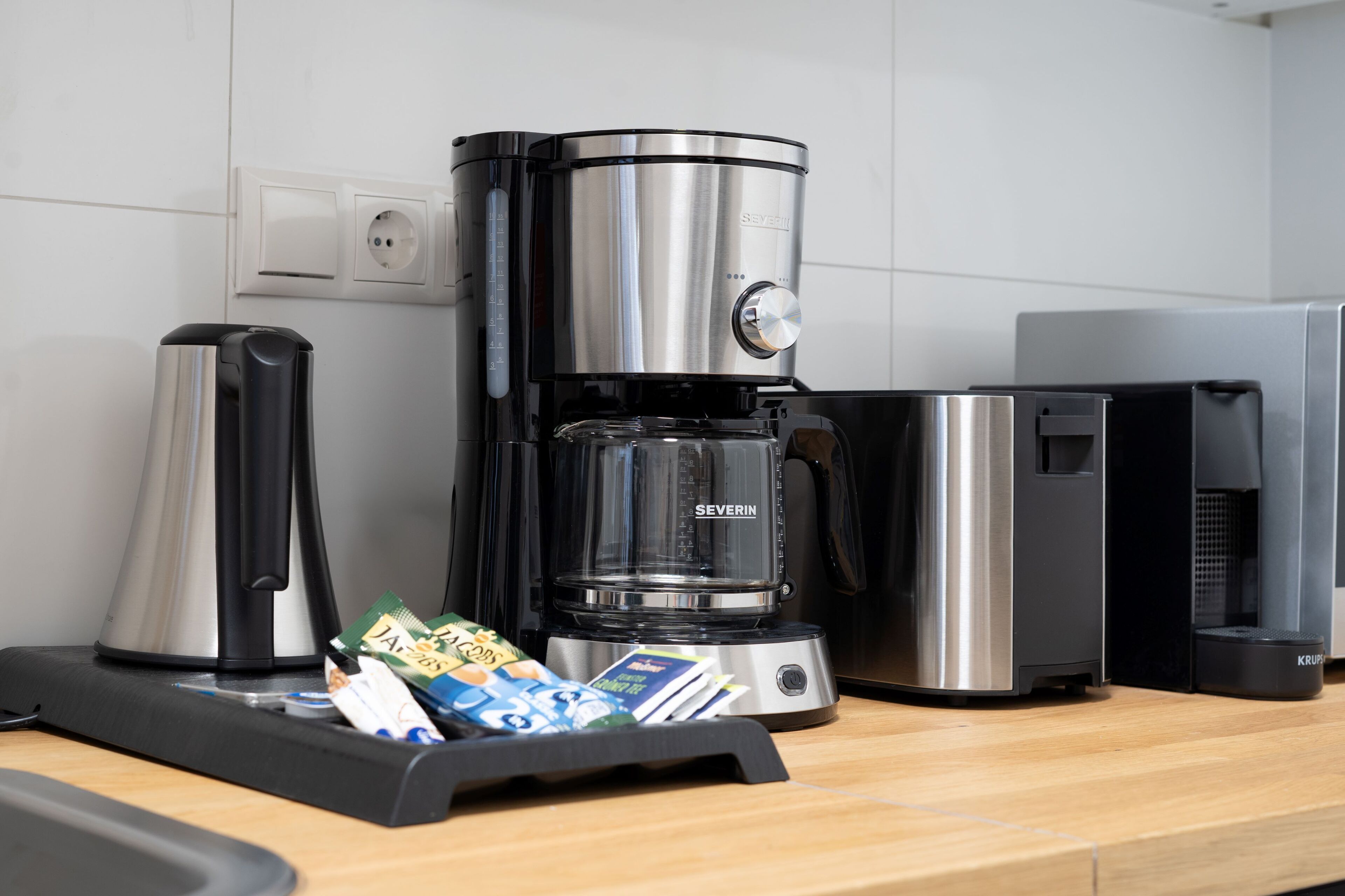 Una cocina moderna con una cafetera, un tostador y una tetera sobre la encimera.
