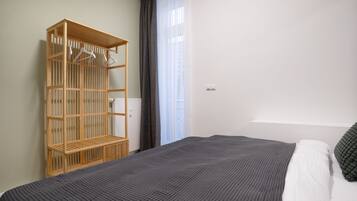 A bedroom with a bed, a wooden wardrobe, and a window with curtains.