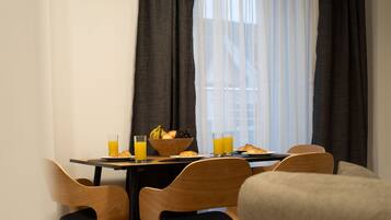 A breakfast table with a bowl of fruit, croissants, and orange juice glasses.
